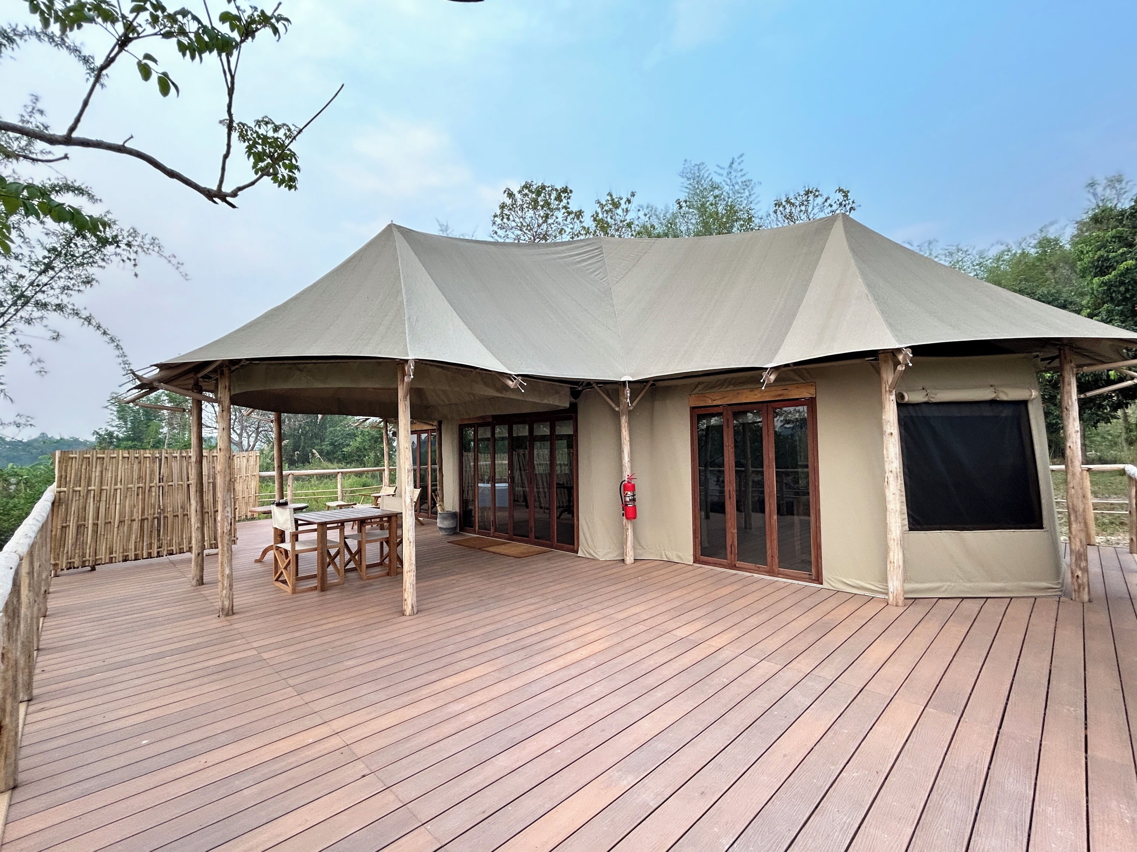 A covered outdoor deck with wooden furniture and a fire extinguisher.