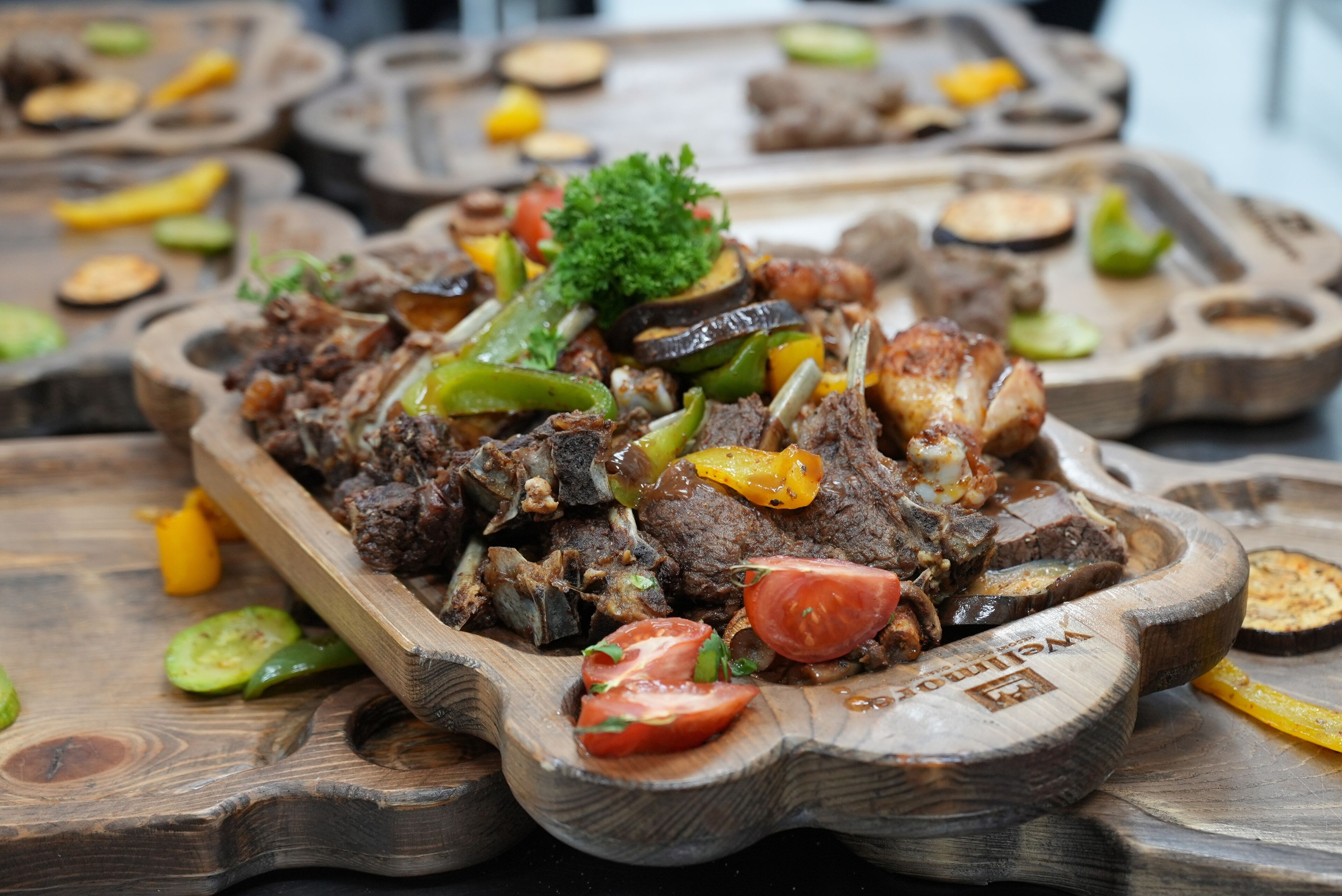 A wooden serving tray with a dish of meat and vegetables.