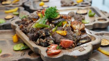 A wooden serving tray with a dish of meat and vegetables.