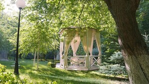 Un jardín exuberante con un quiosco y un farol cercano.