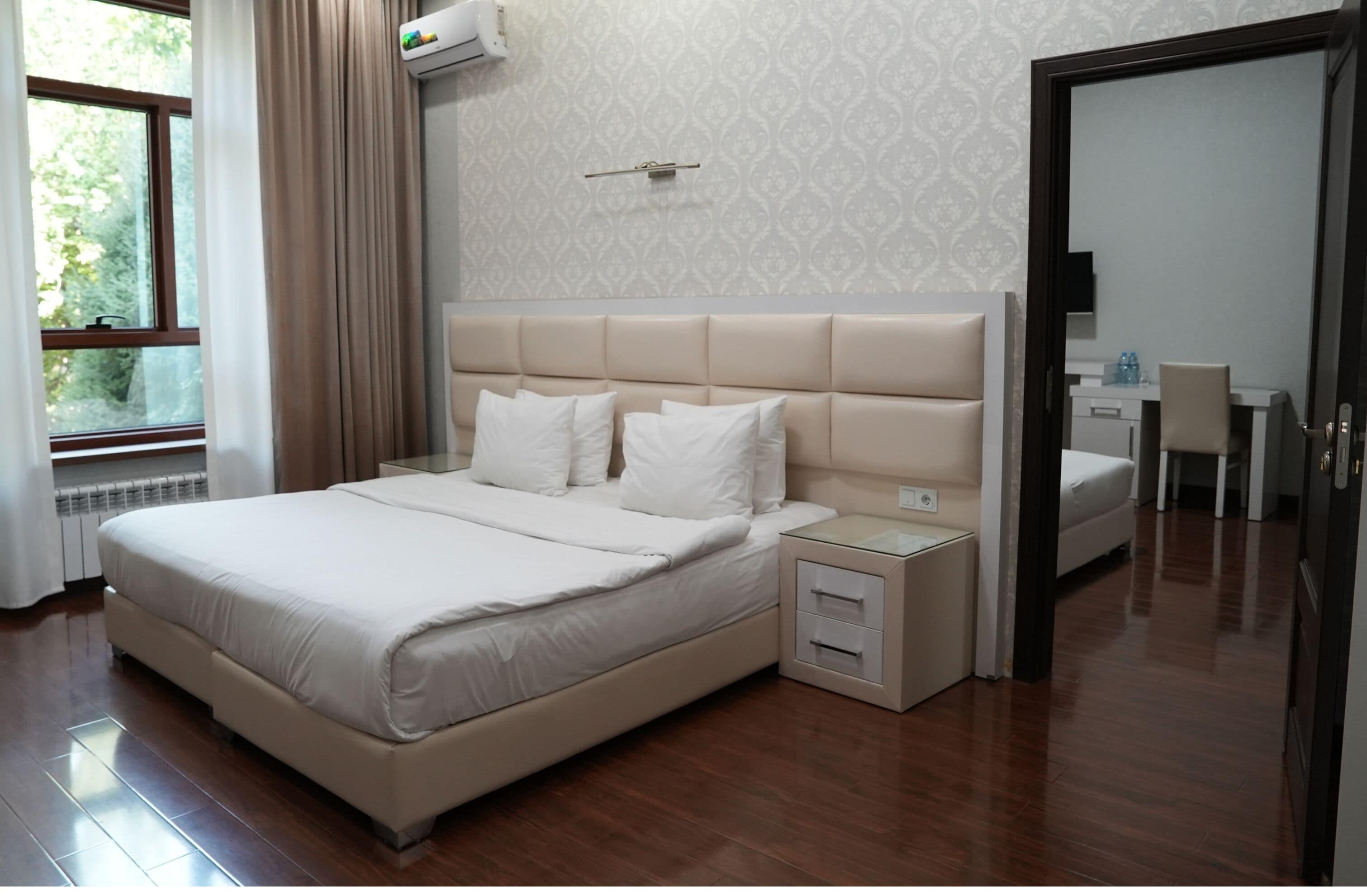 Una habitación de hotel moderna con una cama grande, mesitas de noche, un escritorio y un armario.