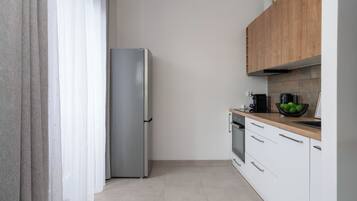 A modern kitchen with a stainless steel refrigerator, wooden cabinets, and a tiled backsplash.