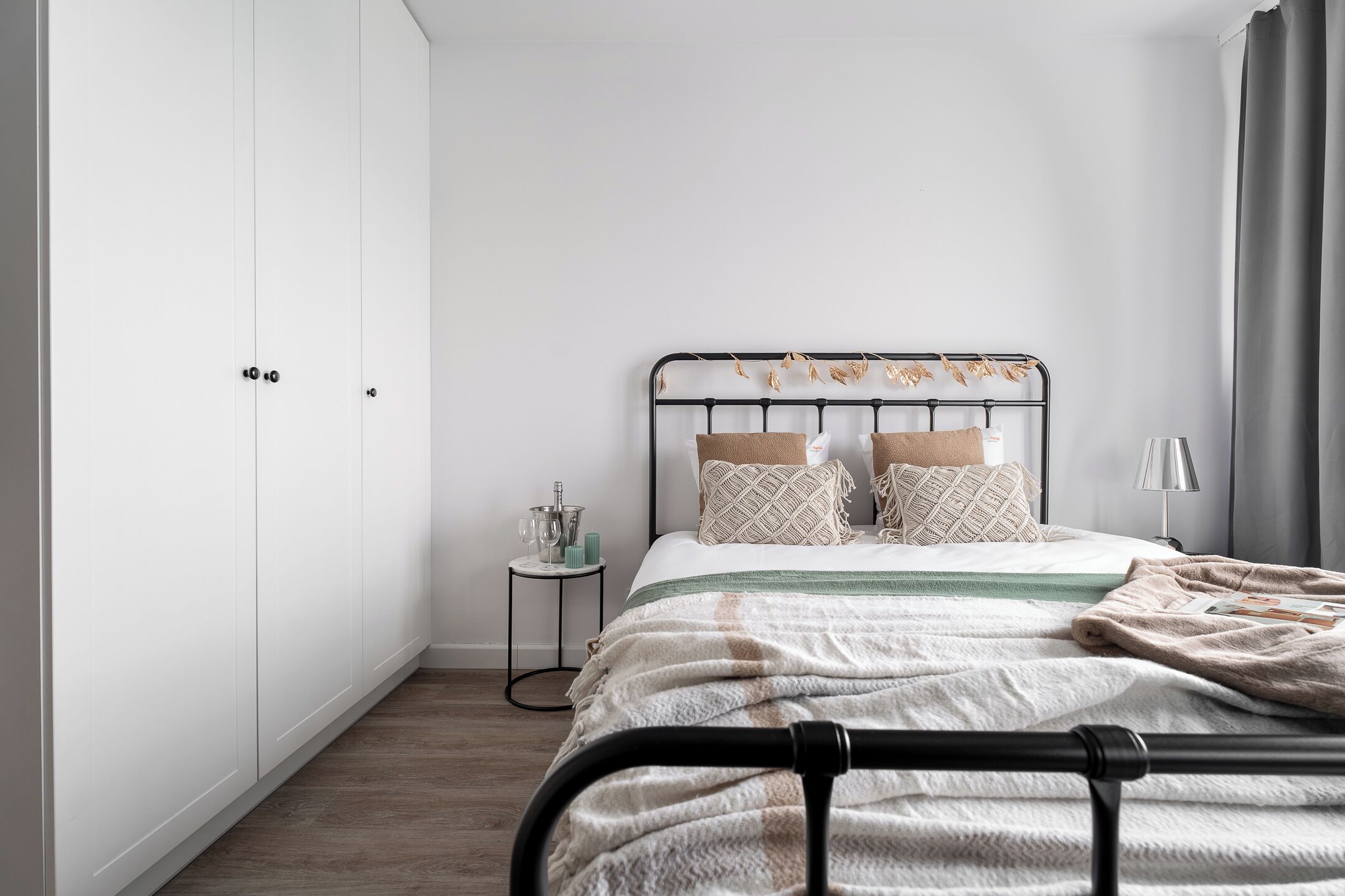 A bedroom with a bed, a wardrobe, a bedside table, and a lamp.