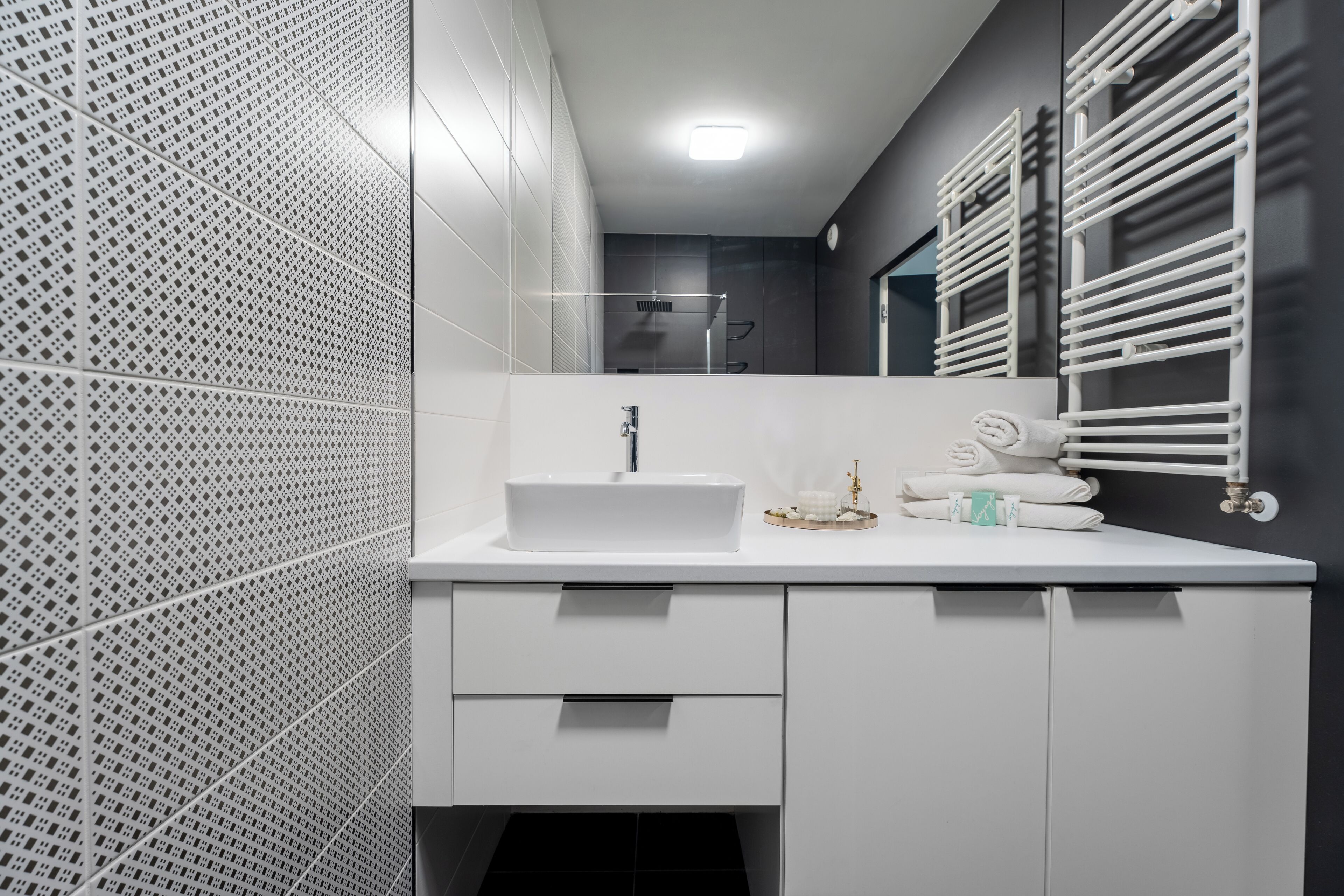 A modern bathroom with a white sink, a mirror, and a towel rack.