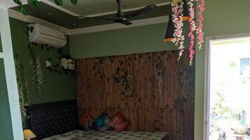 Une chambre à coucher avec un lit, une chaise, un plancher en bois, un ventilateur de plafond et une fenêtre.