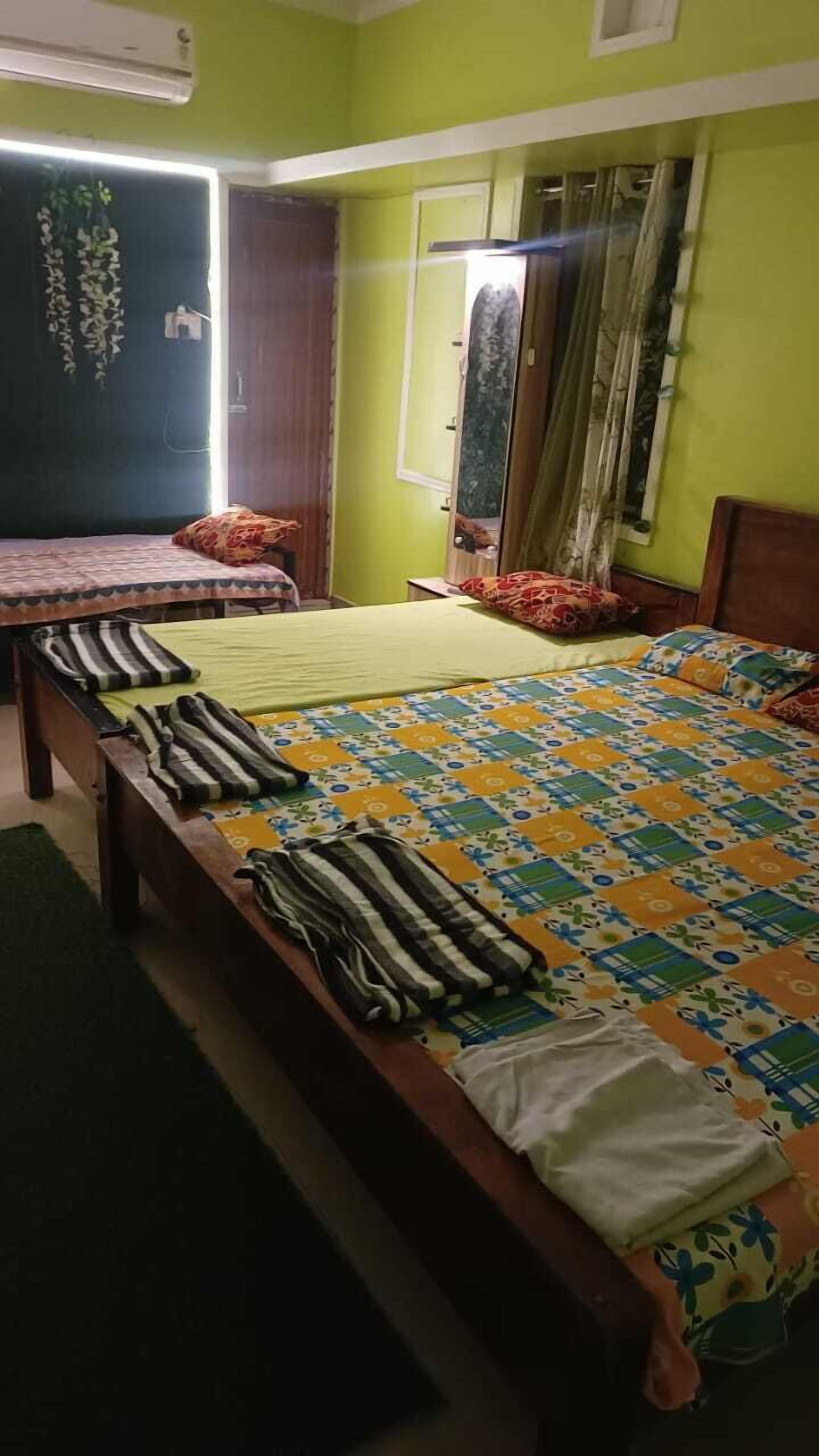 A bedroom with two beds, a mirror, and a window with curtains.