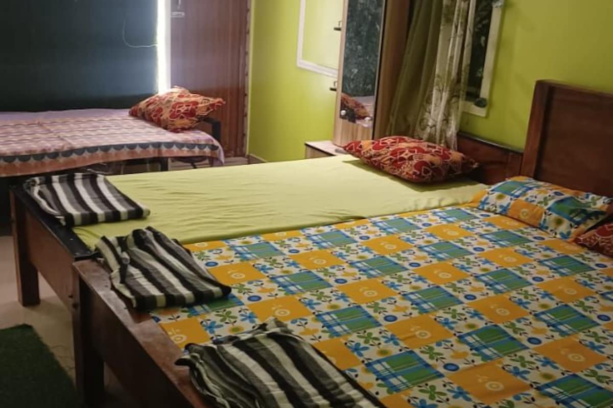 A bedroom with two beds, a mirror, and a window with curtains.
