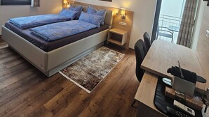 Um quarto moderno com uma cama grande, mesas de cabeceira, uma escrivaninha e uma cadeira.