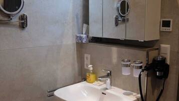 Un baño moderno con un lavamanos blanco, un espejo y un armario.