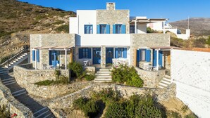 Un edificio a due piani con facciata in pietra, persiane blu e una scalinata che conduce all'ingresso.