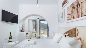 Una camera d'hotel moderna con un letto, una TV, una bottiglia di vino e vista sull'esterno.