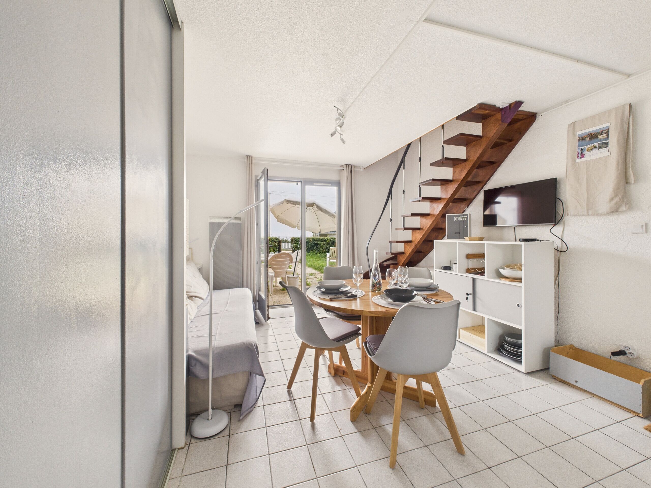 A modern interior with a dining area, a staircase, and a TV mounted on the wall.