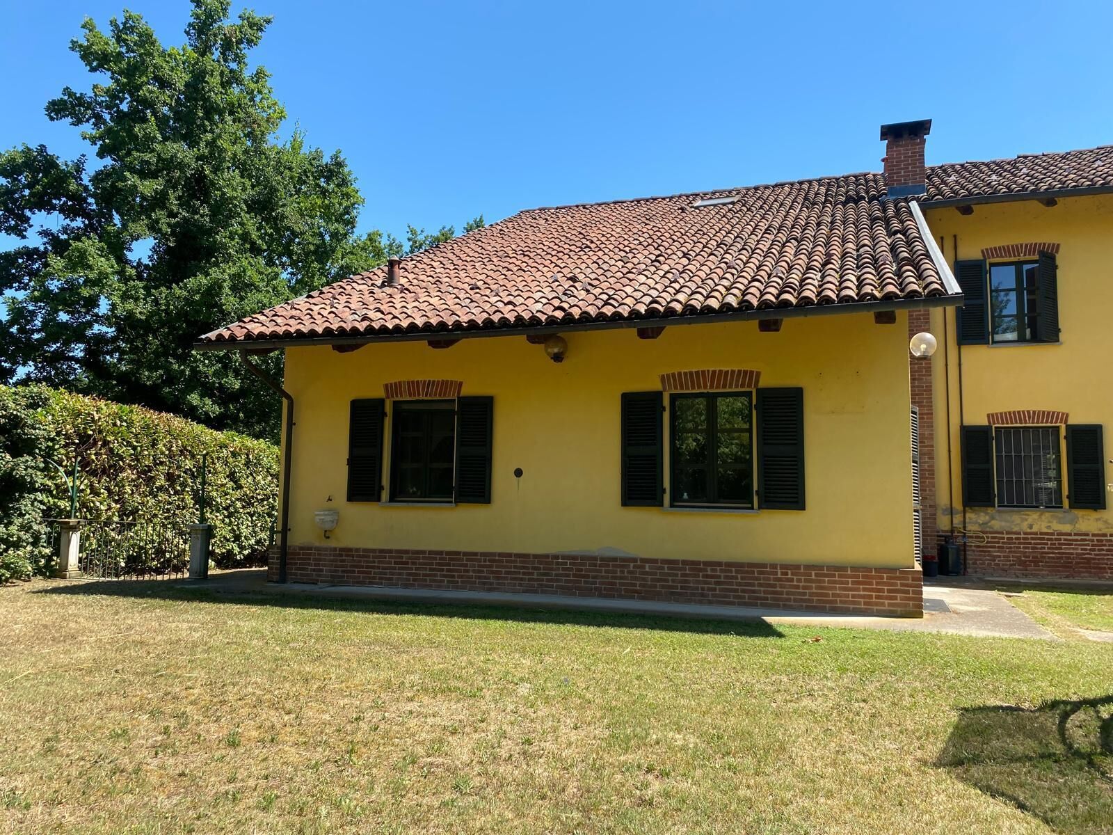 Un edificio giallo con tetto in tegole e due finestre con persiane.