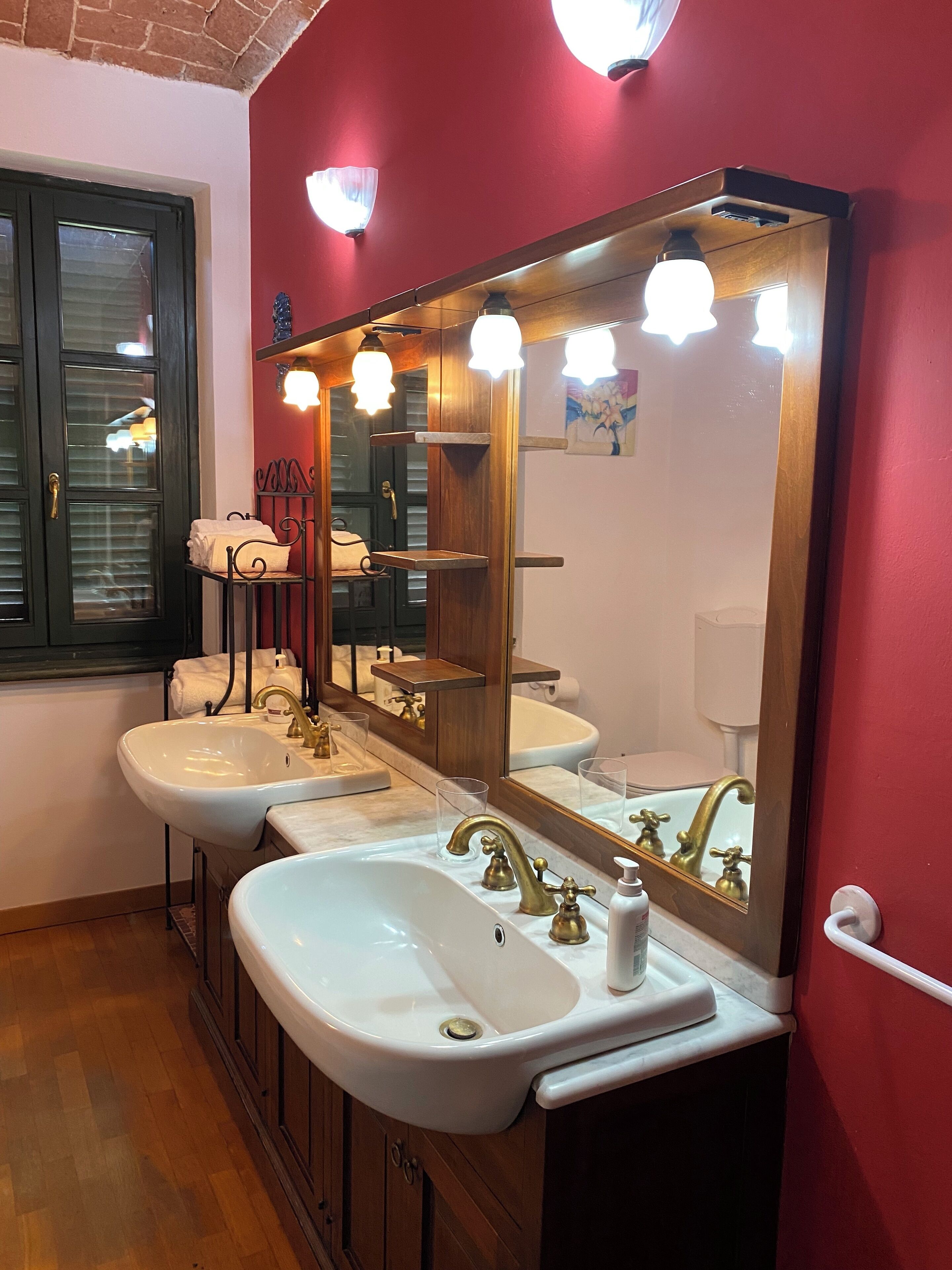 Une salle de bain avec deux lavabos, un miroir et une fenêtre avec des stores.