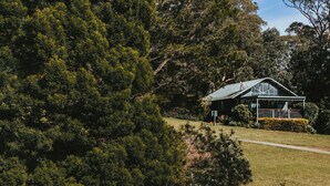 A modern building with a green roof, surrounded by dense green trees and a well-maintained lawn. - Jimmy’s Cabin in Kangaroo Valey. Kangaroos, Kookaburras, sleeps 4! (Kangaroo Valley)
