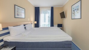 A hotel room with a large bed, two bedside tables, a flat-screen TV, and two framed pictures on the walls. - Vacation Rental: “Apartment on the Zingst Pier with a South-Facing Balcony” (Zingst)