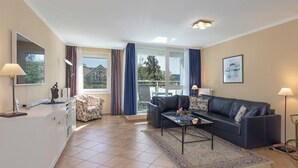 A modern living room with a sofa, coffee table, and a dining area. - Vacation Rental: “Apartment on the Zingst Pier with a South-Facing Balcony” (Zingst)