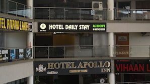 Un hotel con letreros que indican 'Hotel Daily Stay' y 'Hotel Apollo Inn' en el tercer y segundo piso respectivamente.