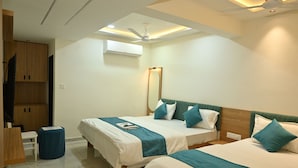 Habitación de hotel con dos camas, ventilador de techo, aire acondicionado y una pequeña mesa con una silla.