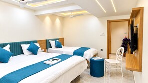 A hotel room with two beds, a desk, a chair, and a TV. - Hotel Daily Stay (Gandhinagar)