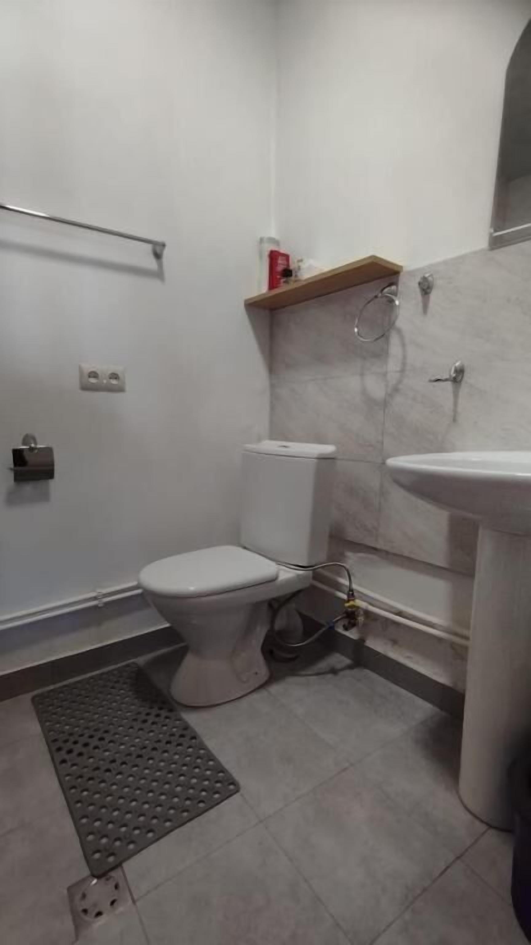A small bathroom with a toilet, a sink, and a shower.