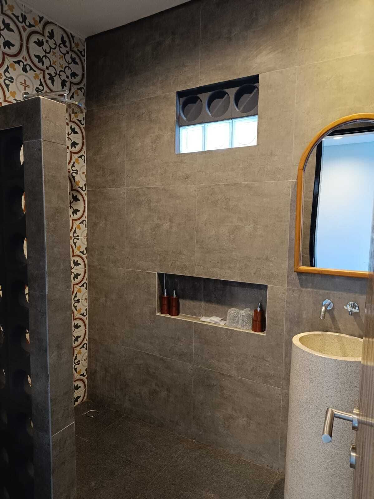 Un baño moderno con una bañera grande, una ventana pequeña y un tocador con espejo.