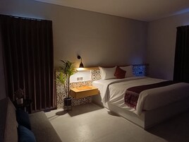 Una habitación de hotel con cama, mesita de noche, lámpara y planta en maceta.