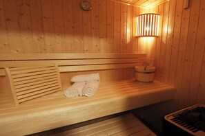 A wooden sauna with benches, a towel rack, and a bucket.
