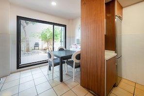 A kitchen with a dining table, chairs, a refrigerator, and a sliding glass door leading to an outdoor area.