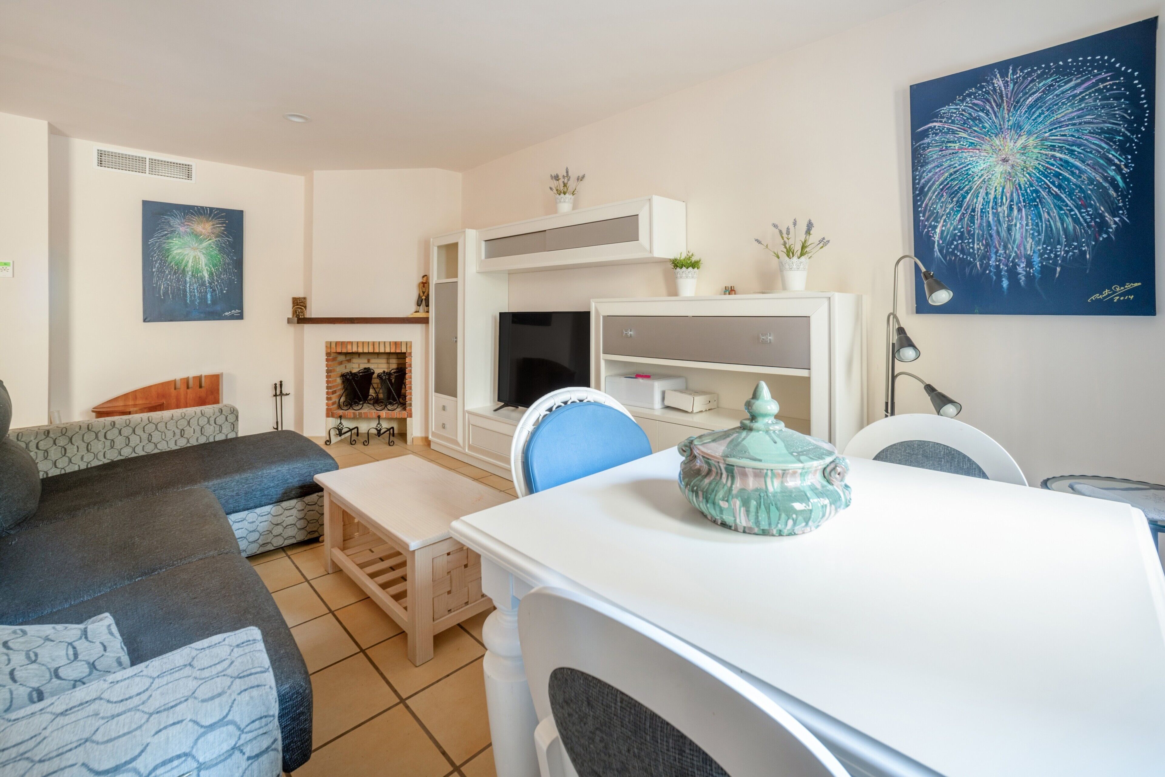 Een woonkamer met een bank, een eettafel, een televisie en een open haard.