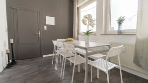 Un coin repas avec une table et des chaises, un vase rempli de fleurs et une fenêtre donnant sur un beau paysage.