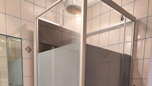 A bathroom with a glass-enclosed shower, a sink, and a mirror. - Le commerce d'Ophelie (Corcieux)