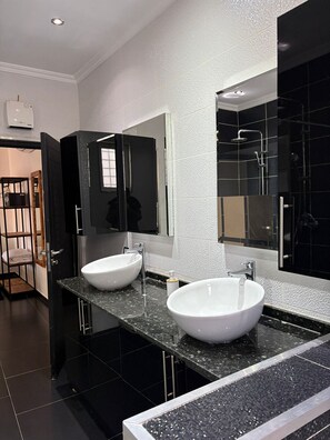 A modern bathroom with two large white sinks, a black vanity, and a large mirror. - Domaine du Douar (Oulad Khallouf)
