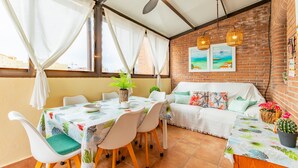 A dining area with a table set for four, a sofa, and a ceiling fan. - Bright Penthouse with Views in Calpe (Calpe)