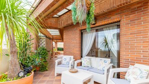 A covered patio with wicker furniture, potted plants, and a brick wall. - Bright Penthouse with Views in Calpe (Calpe)