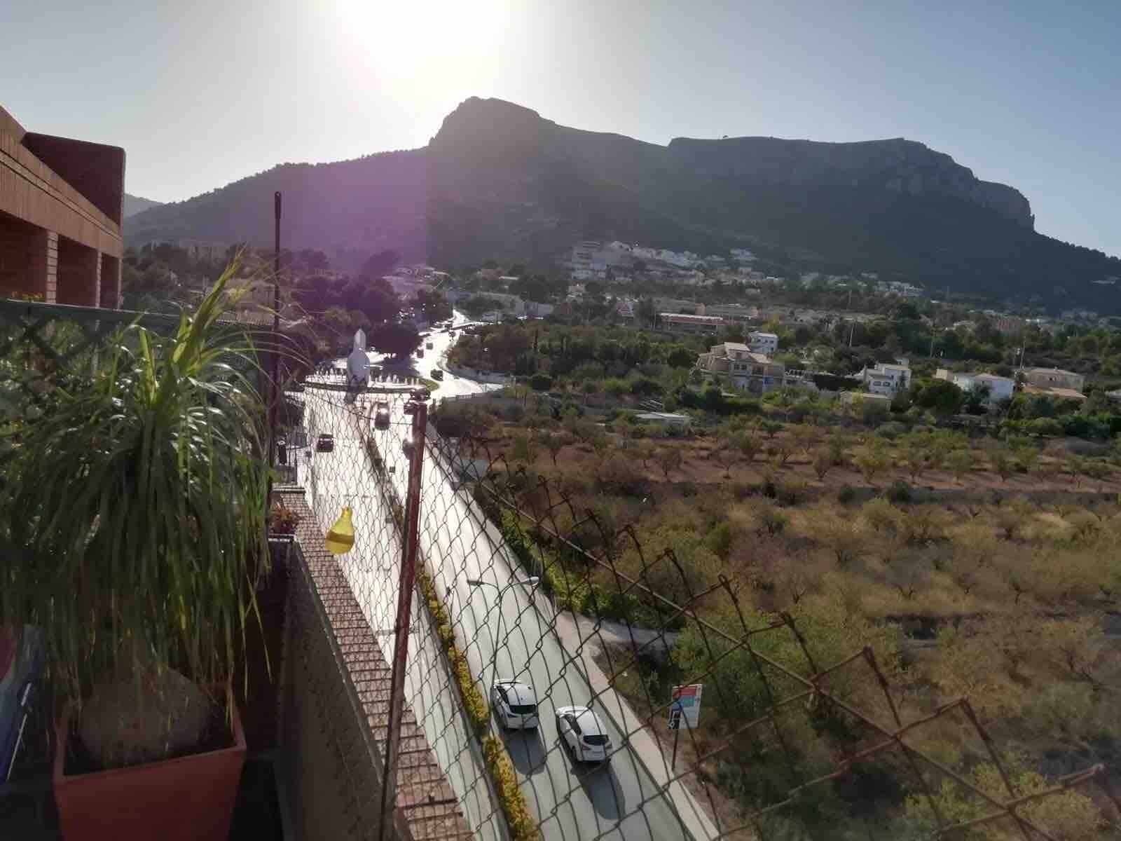 A bridge with a chain-link fence, a river, and a mountain in the background.