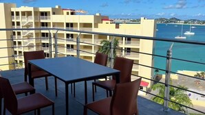 A balcony with a table and chairs, overlooking a marina with boats and a clear blue sky. - Beach Front 4 Bed Condon D2.1 with Sea View and Private Pool !! (Simpson Bay)