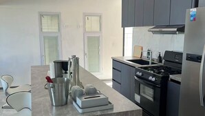A modern kitchen with dark cabinets, a stainless steel refrigerator, a gas stove, and a marble countertop. - Beach Front 4 Bed Condon D2.1 with Sea View and Private Pool !! (Simpson Bay)