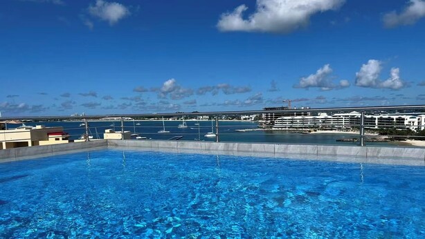A clear blue pool with a view of a marina and buildings in the background. - Beach Front 4 Bed Condon D2.1 with Sea View and Private Pool !! (Simpson Bay)