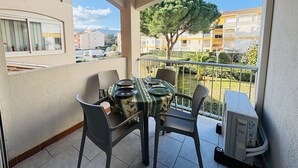 A balcony with a table and chairs, a view of a tree, and a building in the background. - Argelès-sur-Mer - T2 Apartment with Balcony and Parking (Argelès-sur-Mer)