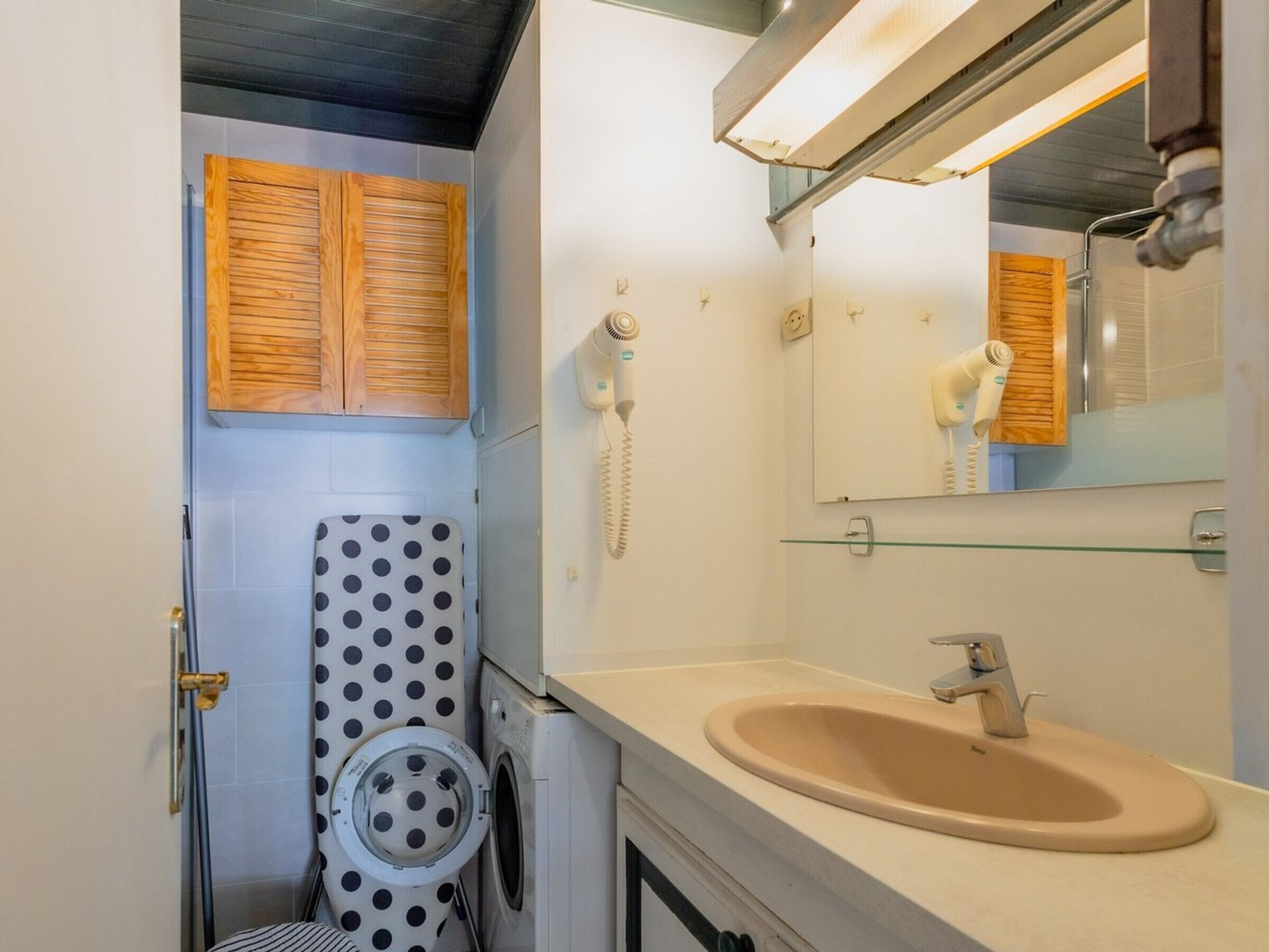 Ein kleines Badezimmer mit Toilette, Waschmaschine und Waschbecken mit Spiegel darüber.
