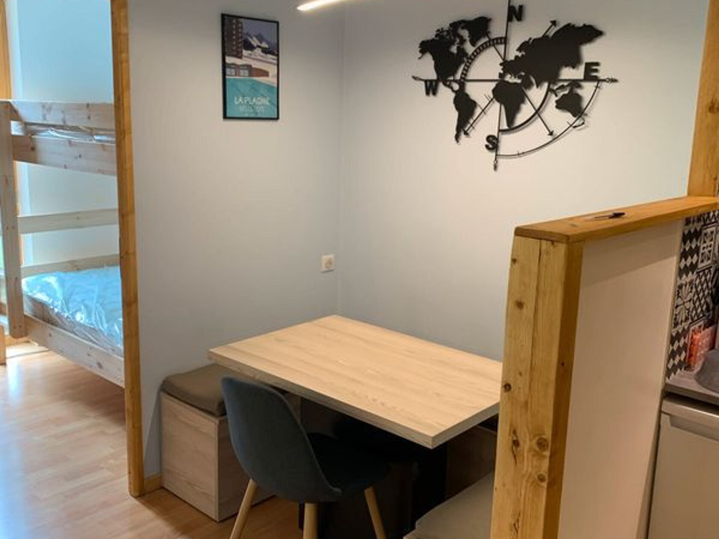 Une petite pièce moderne, avec un bureau en bois, une chaise et une carte du monde accrochée au mur.
