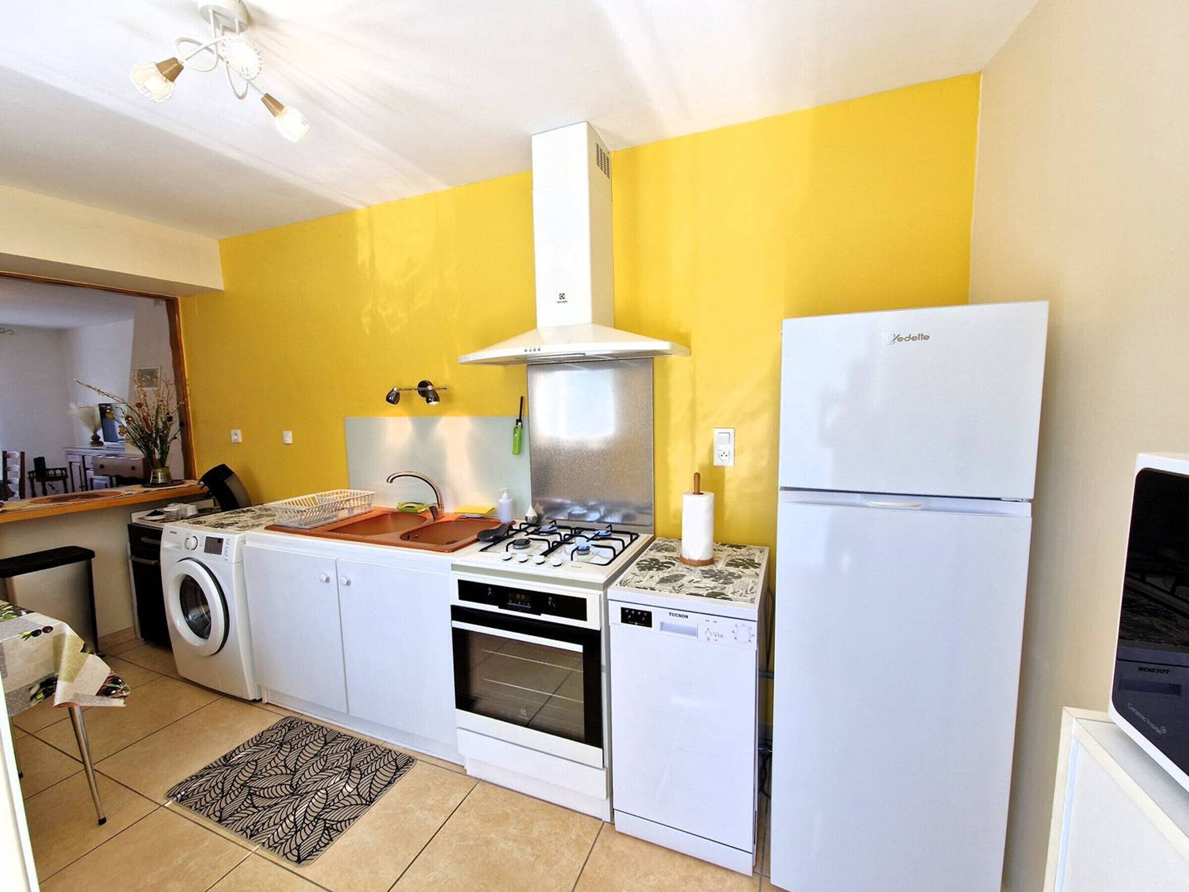 Cozinha compacta com máquina de lavar, fogão, lava-louças e geladeira.
