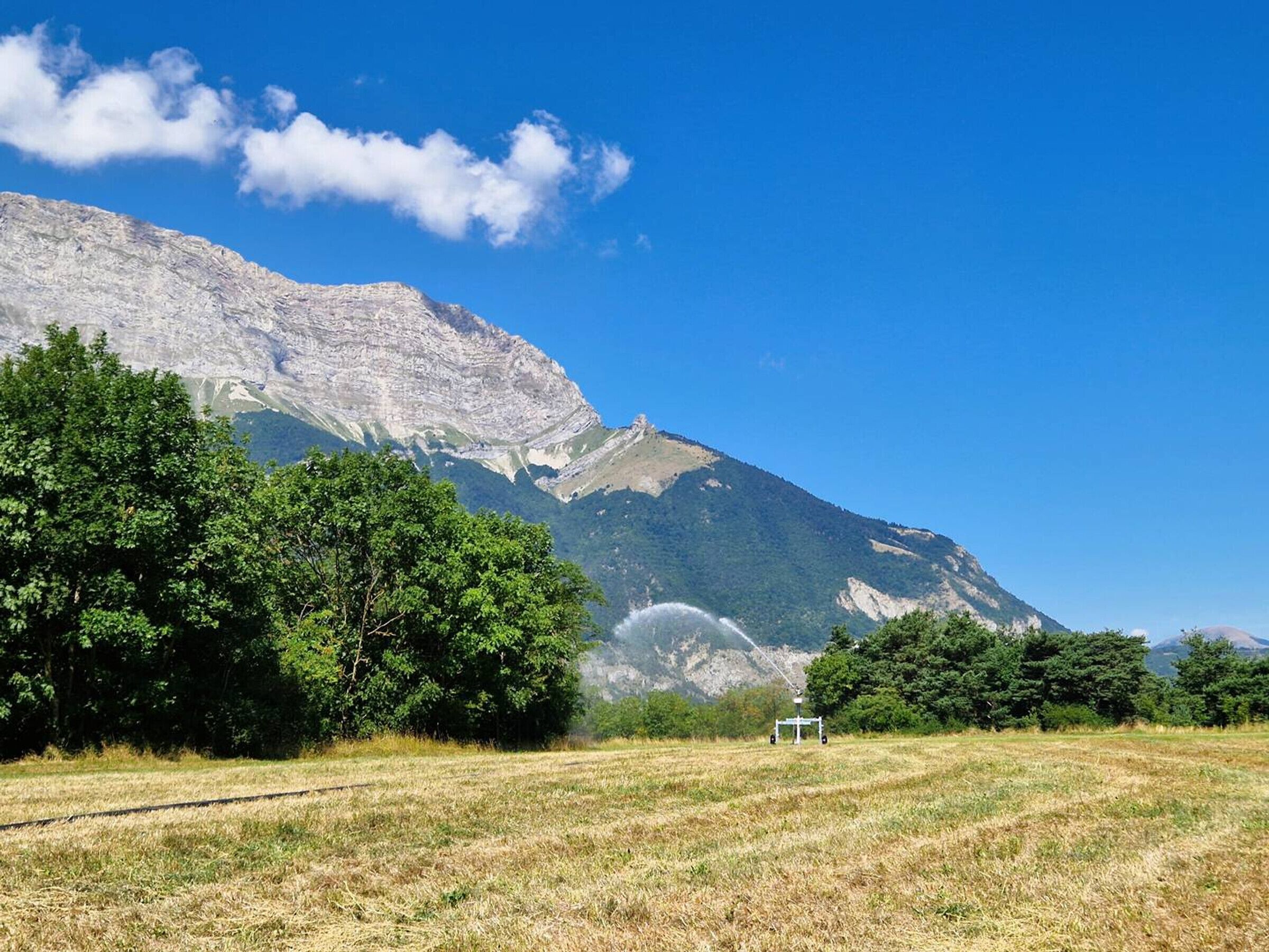 Un paysage montagneux sous un ciel dégagé, avec une voie ferrée et une petite construction au premier plan.