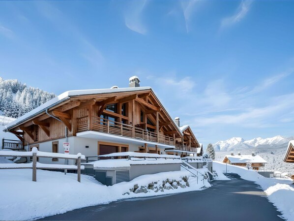 A wooden chalet with a balcony, surrounded by snow-covered mountains and a clear sky. - 2BR Apartment in Les Saisies, sleeps 6 (Les Saisies)