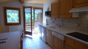 A kitchen with wooden cabinets, a microwave, a sink, and a window overlooking a balcony.