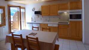 A kitchen with wooden cabinets, a microwave, a stove, and a dining table with chairs.