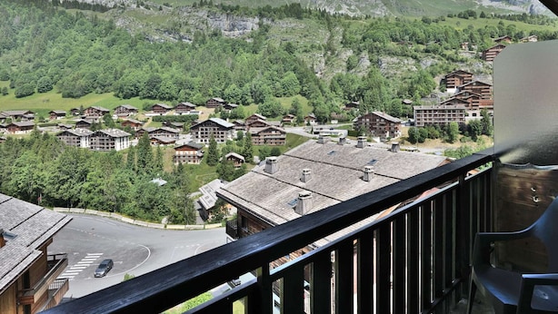 Un village de montagne aux maisons traditionnelles en bois, avec une route dégagée et une vue sur les montagnes environnantes.