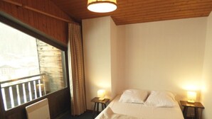 Une chambre avec une grande fenêtre, un plafond en bois et deux lampes de chevet.