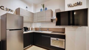 A modern kitchen with a built-in oven, a dishwasher, and a large flat-screen TV mounted above the countertop. - Elegant Apartment - 2bd/6p - Hotel de Ville (Paris)